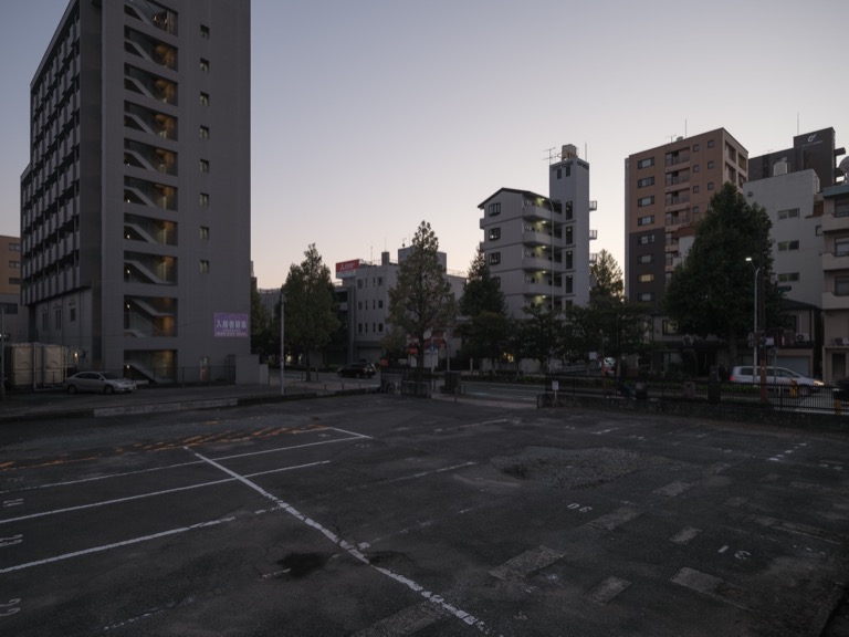Parking lot in the city center at dusk, with the sky still bright for nighttime.